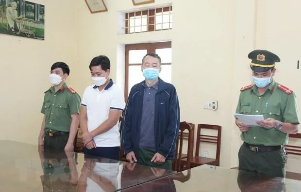 Cơ quan An ninh điều tra đọc lệnh bắt tạm giam đối tượng Khánh và An. (Ảnh: Hoàng Nguyên/TTXVN).