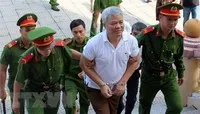 Lực lượng chức năng dẫn giải bị cáo Nguyễn Văn Khuê vào phòng xét xử. (Ảnh: Vũ Hà/TTXVN)