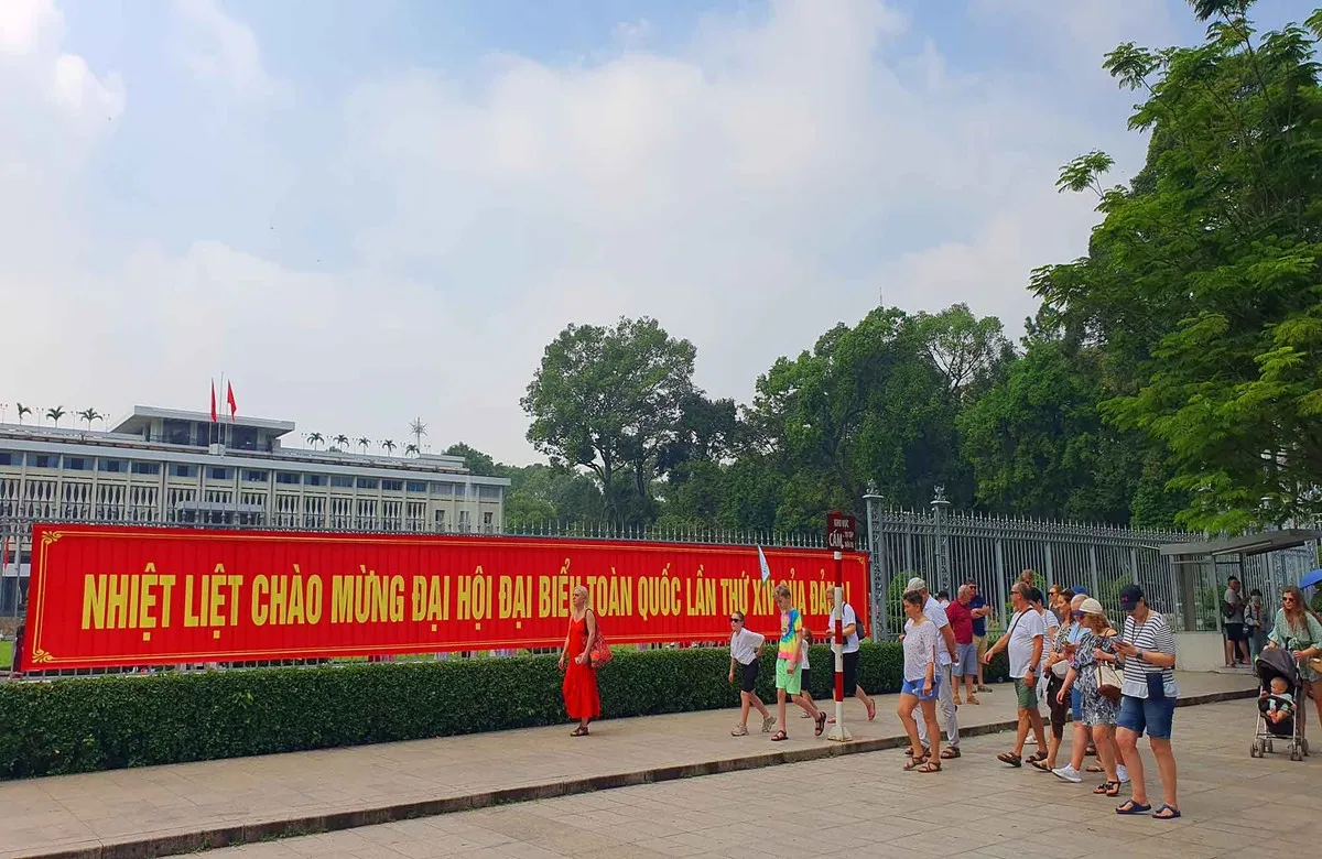 Khách quốc tế và người dân dạo bước qua khu vực treo băng rôn, pano chào mừng Đại hội Đảng, ghi lại những khoảnh khắc về không khí chuẩn bị cho sự kiện chính trị quan trọng của đất nước.