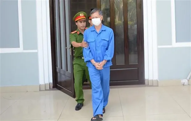 Cơ quan chức năng dẫn giải cựu Giám đốc CDC Đà Nẵng ra xe sau khi kết thúc phiên tòa sáng 25/8. (Ảnh: Văn Dũng/TTXVN)